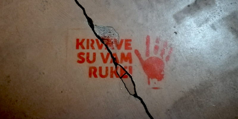 Ein Stencil einer roten Hand mit einer serbischen Parole über ein Riss auf einer Betonfläche in Belgrad. Foto: Aljoscha Hartmann